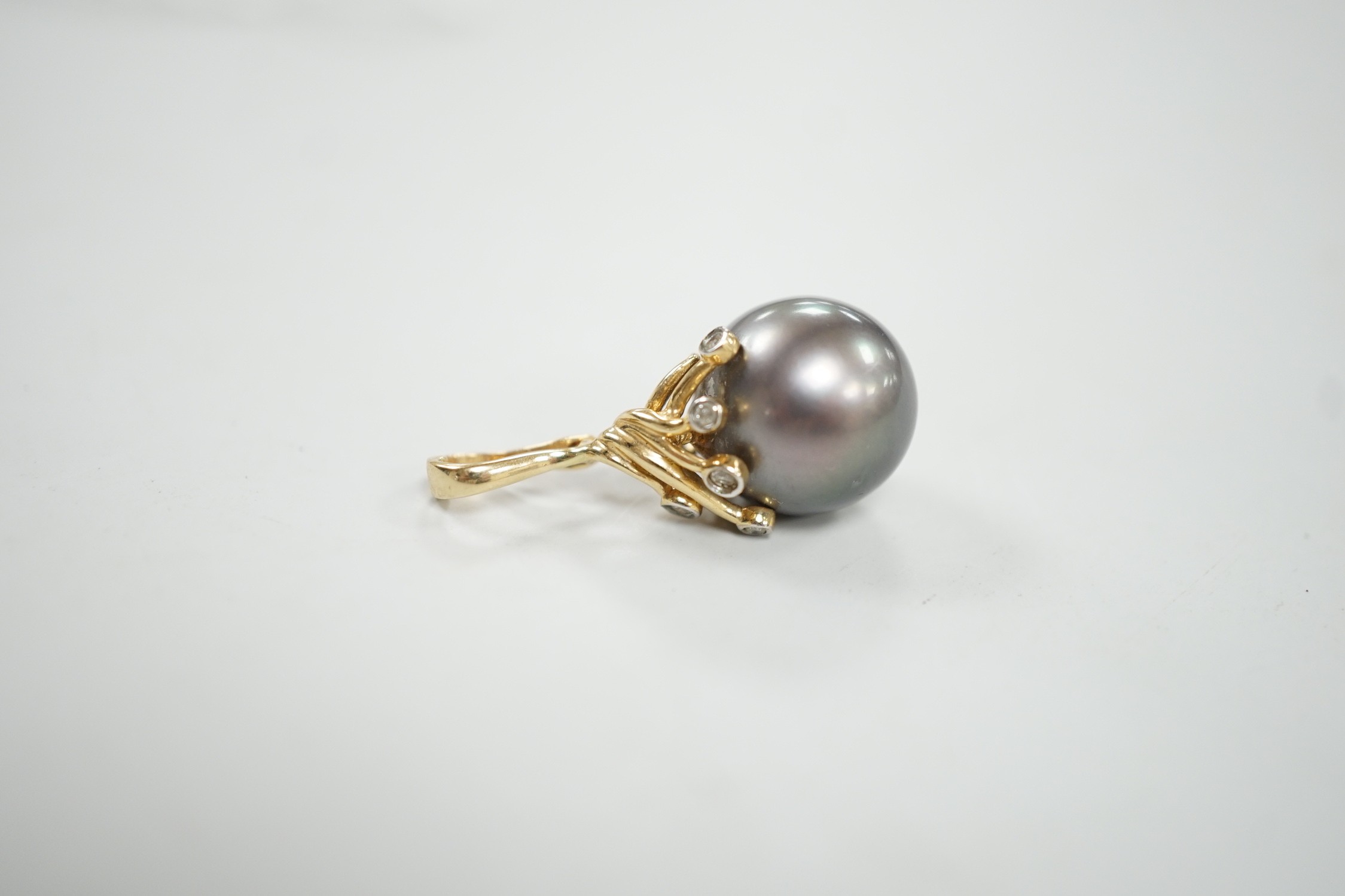 A modern 585 yellow metal, single stone Tahitian pearl and five stone diamond chip set pendant, pearl diameter 13.6mm, 30mm, gross weight 5.4 grams.